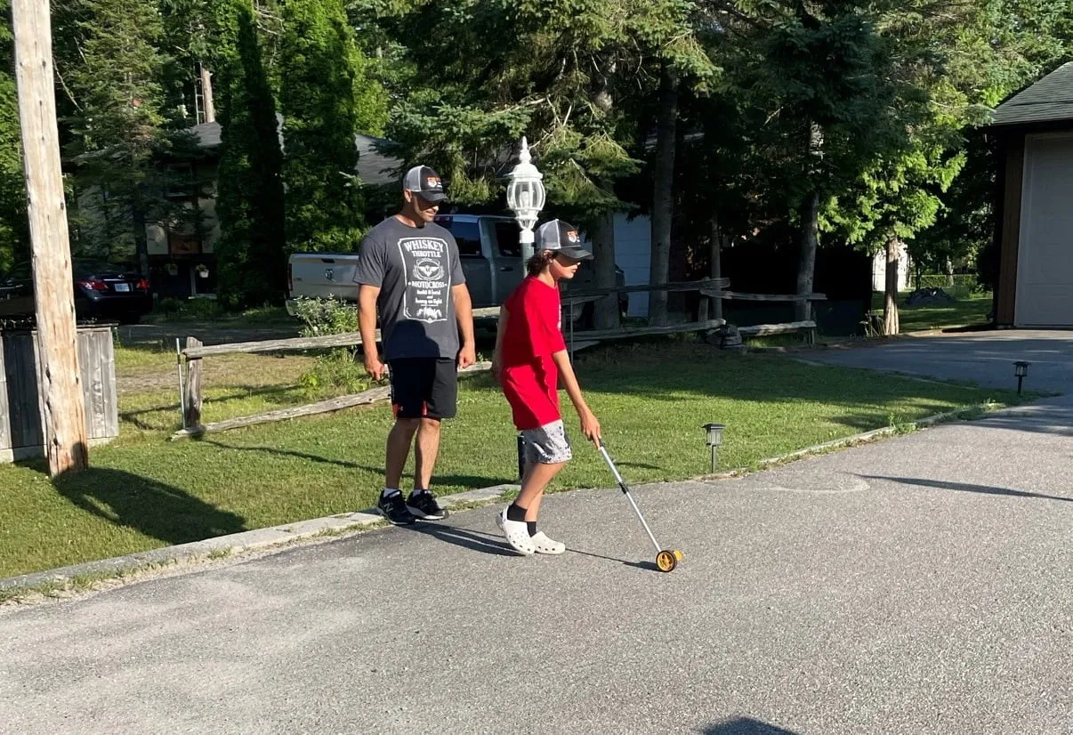 The father-and-son team behind STIX Asphalt Sealcoating measuring a driveway in Tiny Township